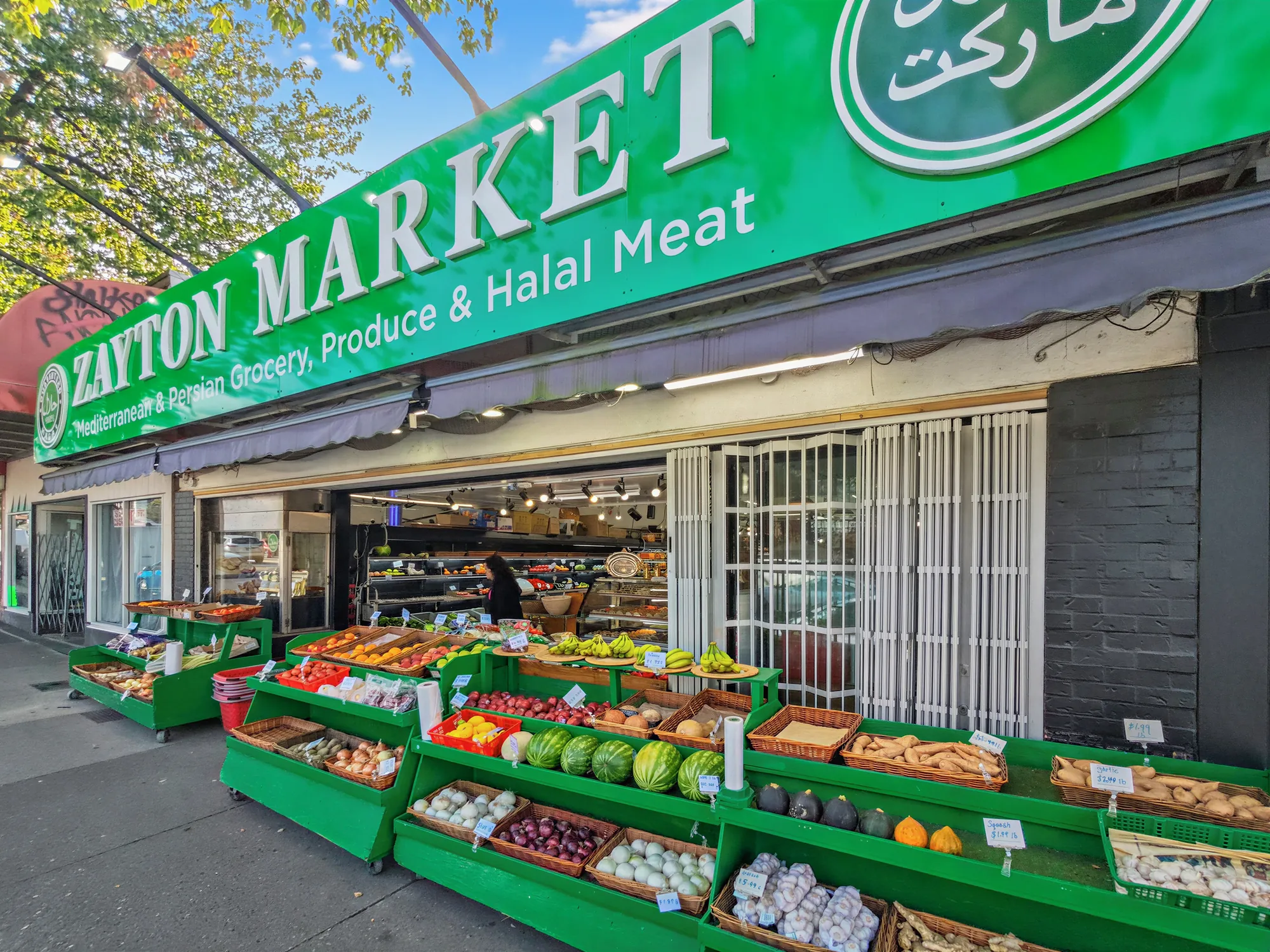 Zayton Market storefront from close in, the sign running over the open shopfront and the produce tables