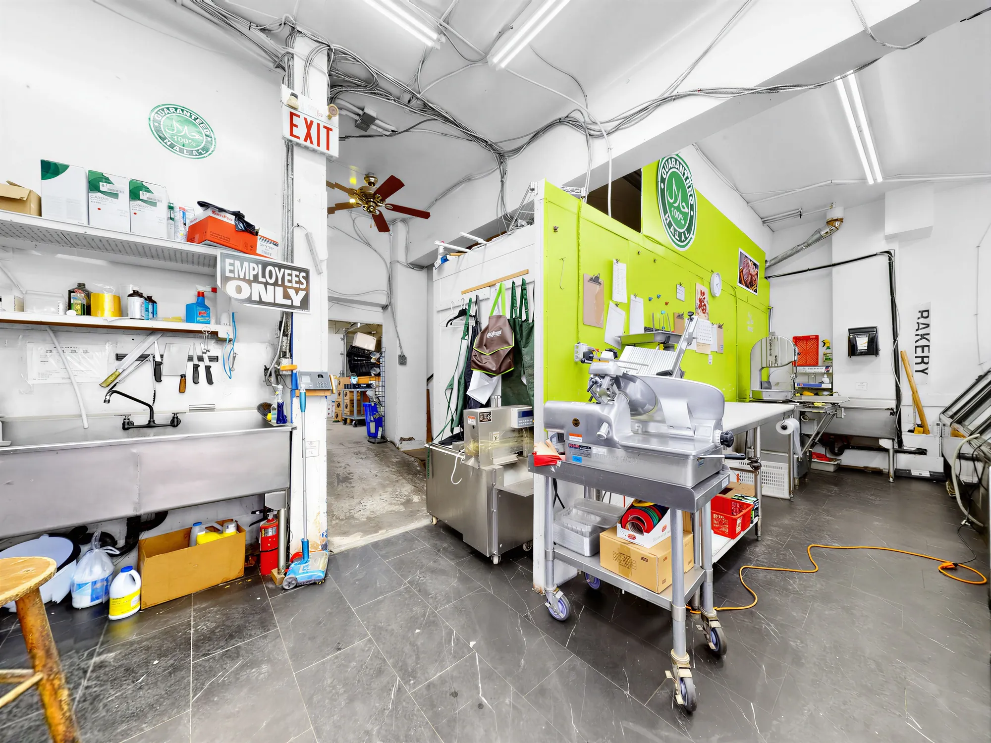 Back prep area with stainless benches, sinks and a meat slicer on a cart